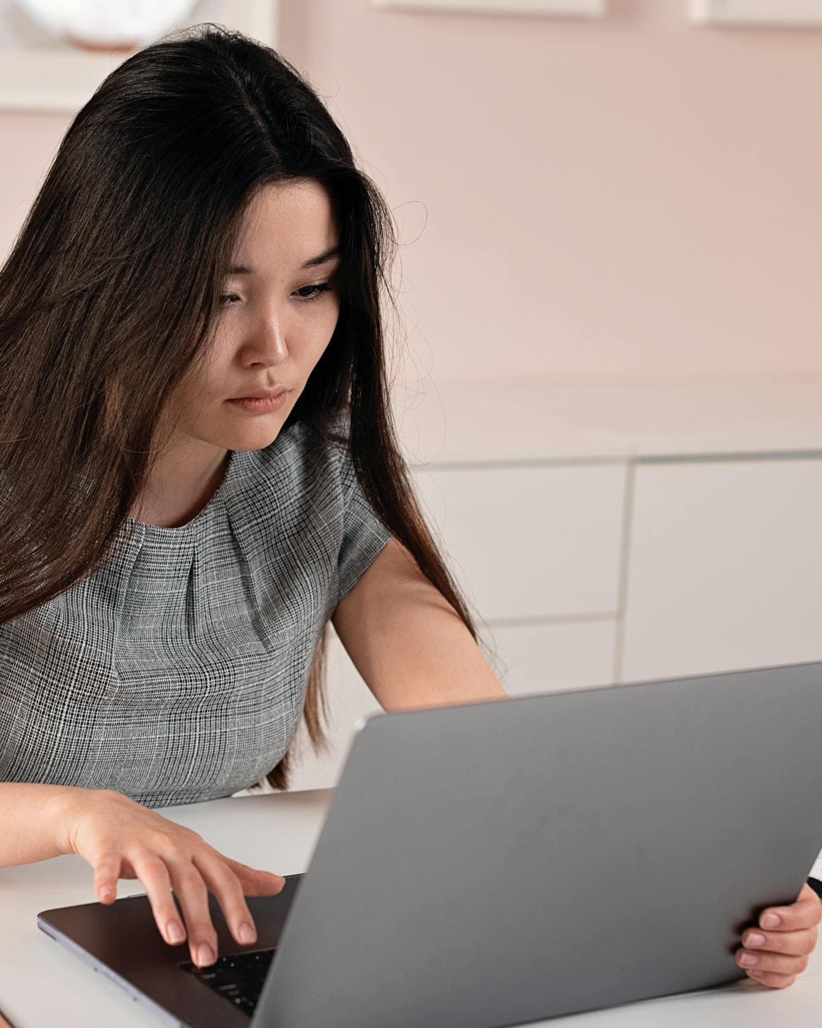 A young professional focused on her laptop in a modern home office